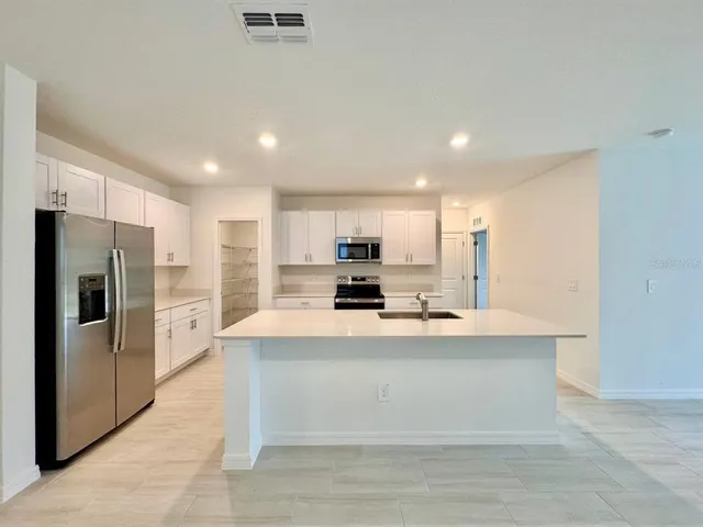 a large white kitchen with cabinets and stainless steel appliances