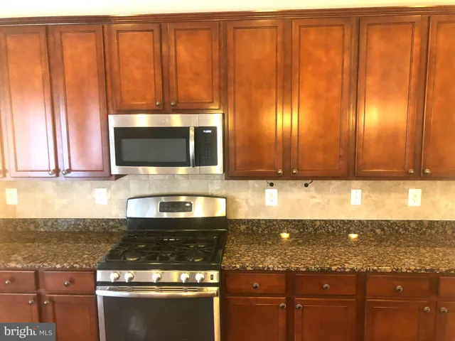 a kitchen with granite countertop a stove a sink and a microwave