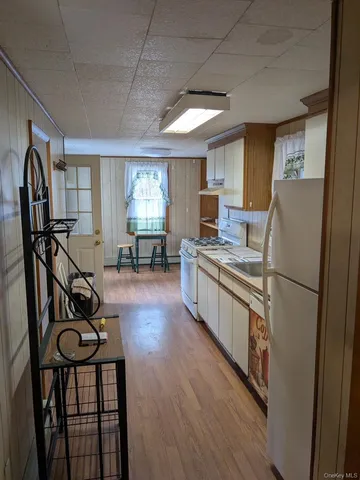 a kitchen with stainless steel appliances granite countertop a refrigerator a stove a sink a dining table and chairs with wooden floor