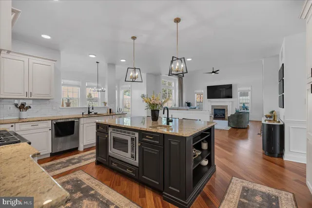 a kitchen with stainless steel appliances granite countertop a stove top oven a sink dishwasher a dining table and chairs with wooden floor