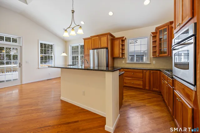 a view of a kitchen with stainless steel appliances granite countertop a stove and a wooden floors
