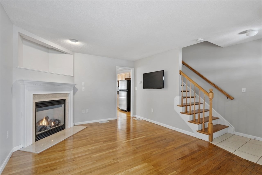 181 High Street, Unit 2 Andover, MA 01810 - Photo 5 of 32 a view of a livingroom with wooden floor and fireplace