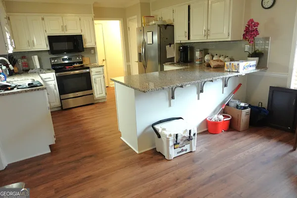 a kitchen with stainless steel appliances granite countertop a refrigerator stove and wooden floor