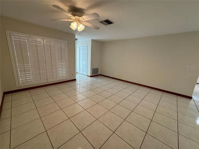 a view of a livingroom with a chandelier fan and windows