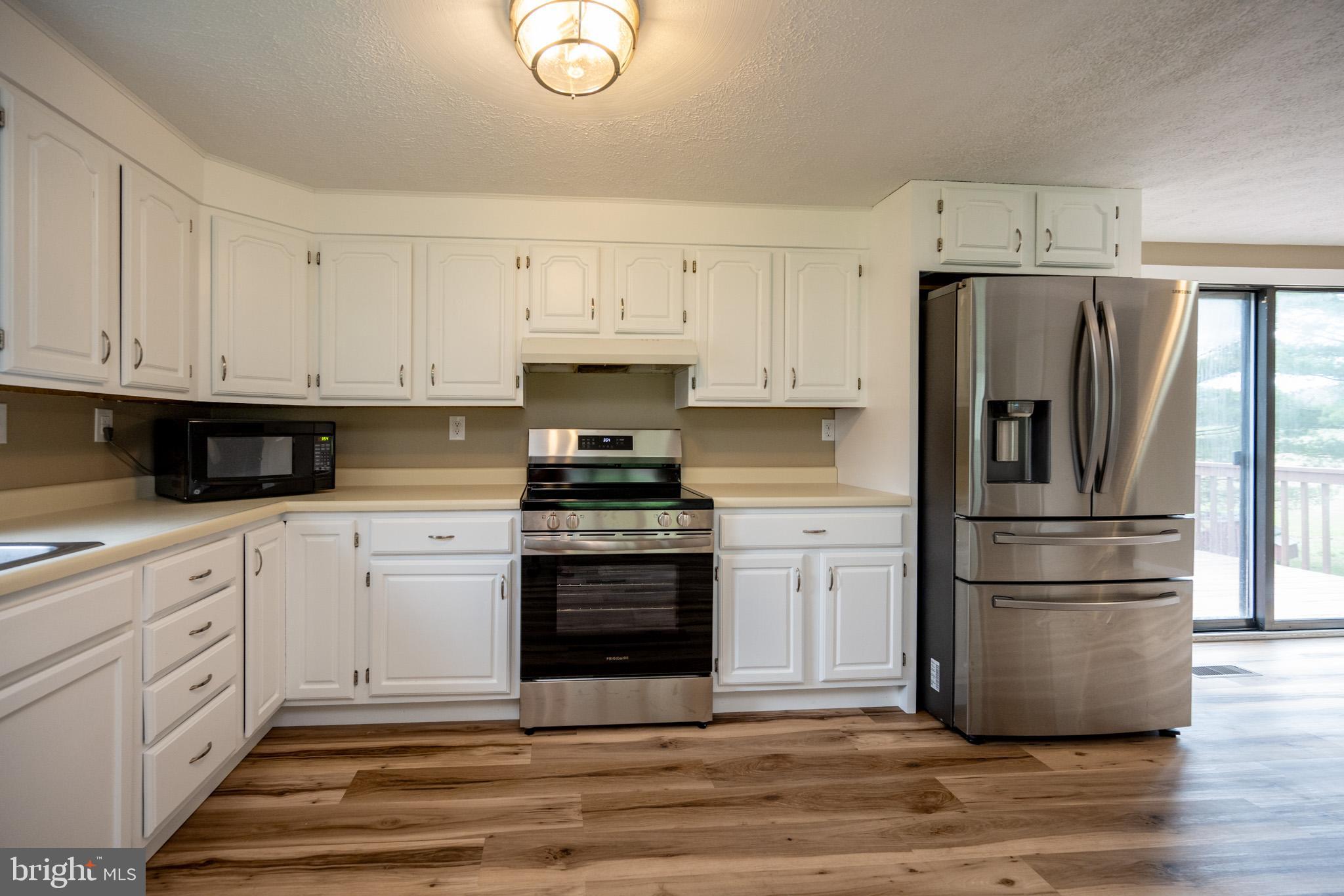 2571 Shady Dell Road Oakland, MD 21550 - Photo 9 of 60 a kitchen with white cabinets and stainless steel appliances