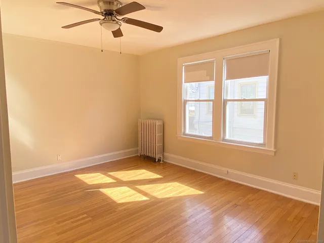 a view of an empty room with a window and wooden floor