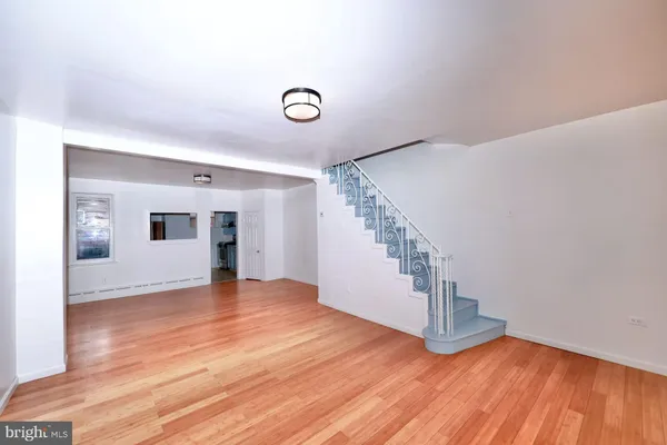a view of an empty room with wooden floor and stairs