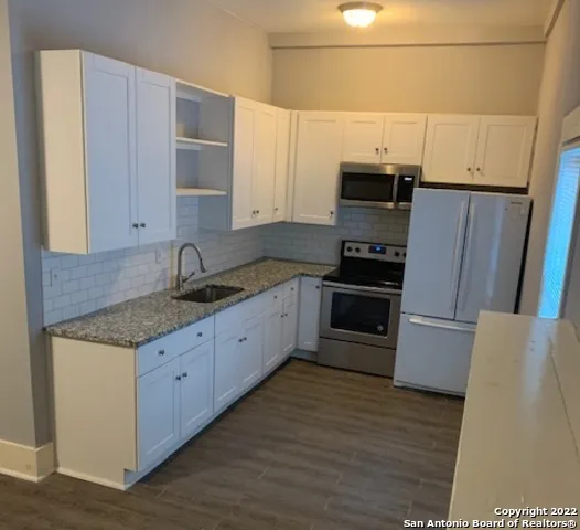 a kitchen with granite countertop a refrigerator and a sink