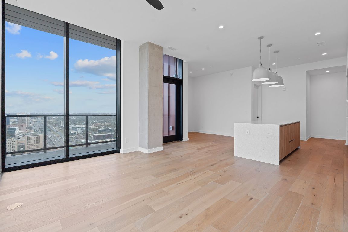 84 East Avenue, Unit 4001 Austin, TX 78701 - Photo 21 of 40 Unfurnished living room featuring a wall of windows, light wood-style flooring, and recessed lighting with dining nook