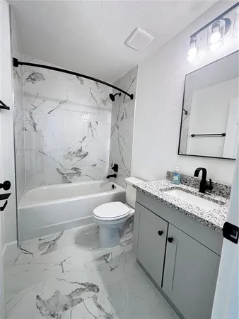 a bathroom with a granite countertop sink toilet a mirror a bathtub and shower