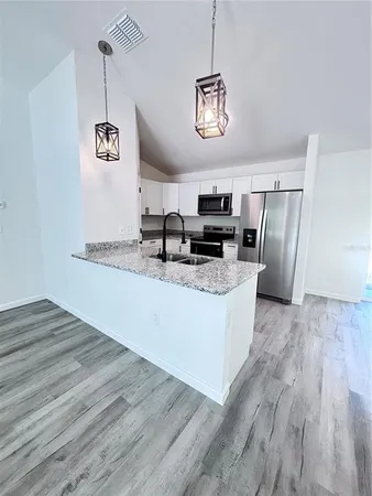 a kitchen with stainless steel appliances granite countertop a refrigerator a stove and a wooden floors