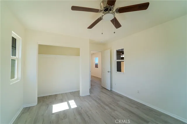 an empty room with wooden floor closet and fan