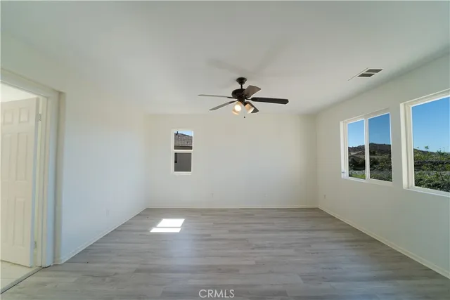 a view of empty room with wooden floor and fan