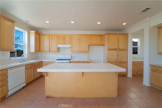 a large kitchen with stainless steel appliances a large counter top a stove a sink and a refrigerator