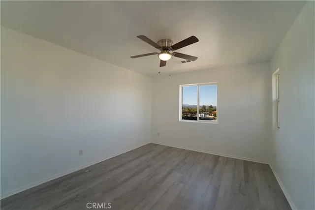 an empty room with wooden floor and ceiling fan
