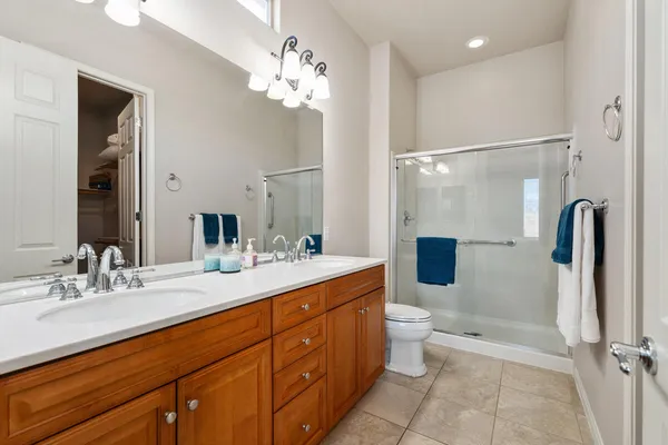 a spacious bathroom with a double vanity sink toilet mirror and shower