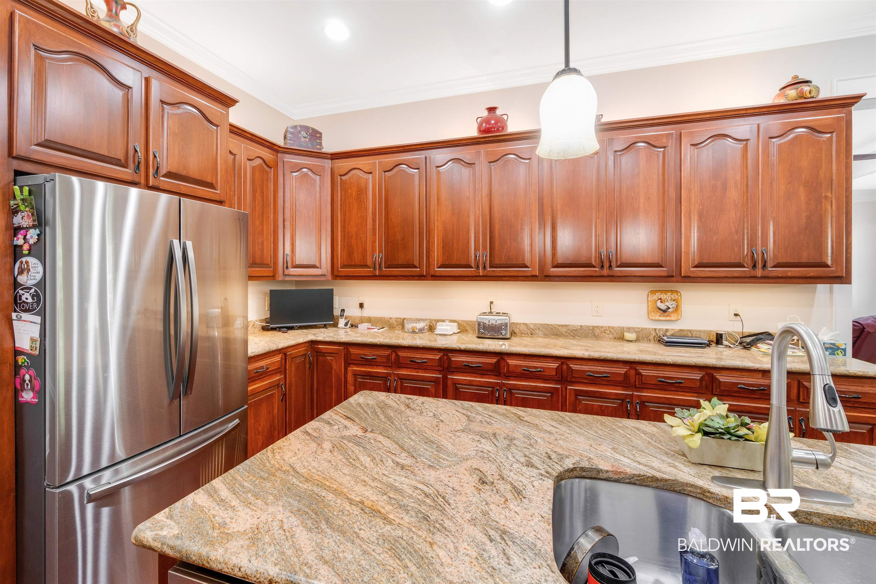 11281 Redfern Road Daphne, AL 36526 - Photo 20 of 80 Kitchen featuring pendant lighting, ornamental molding, stainless steel fridge, light stone counters, and sink