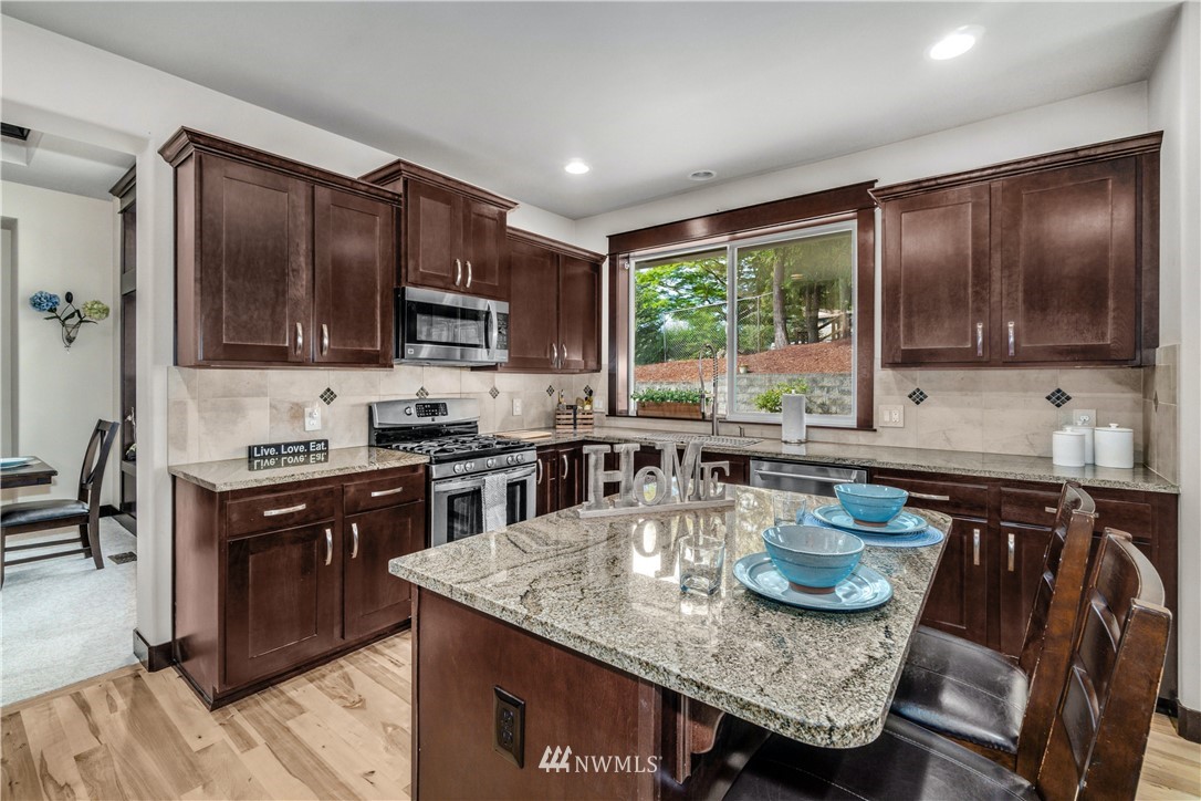 23522 2nd Avenue Southeast Bothell, WA 98021 - Photo 14 of 38 a kitchen with stainless steel appliances granite countertop a stove a sink a microwave dining table and chairs