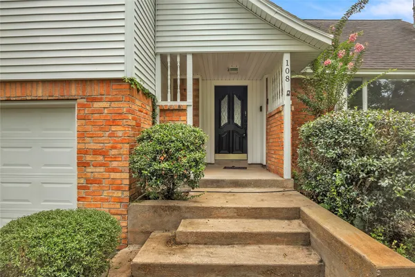 a front view of a house with a garden and trees