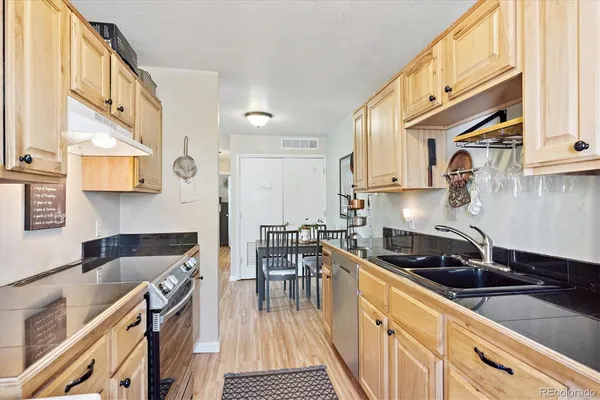 a kitchen with stainless steel appliances a sink a stove and a wooden cabinets