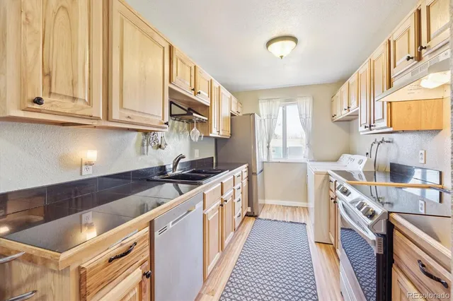 a kitchen with stainless steel appliances granite countertop a stove a sink and a refrigerator