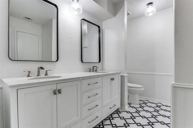 a bathroom with double vanity sink a mirror and a toilet