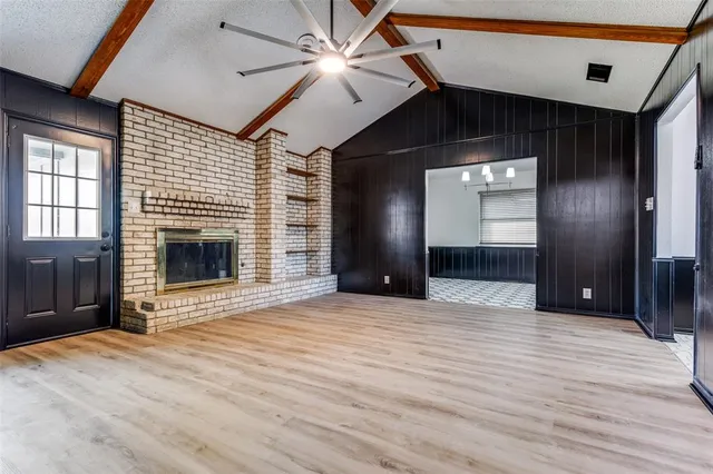 a view of an empty room with wooden floor and a fireplace