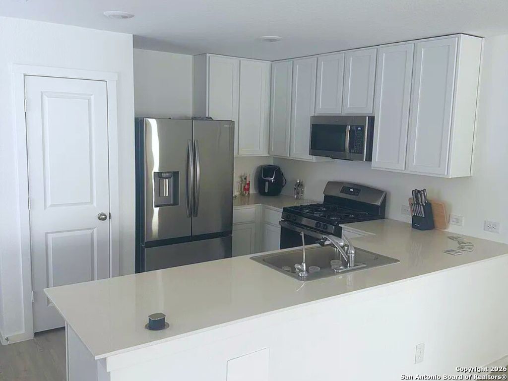 3703 Millbrook Way San Antonio, TX 78245 - Photo 2 of 10 a kitchen with kitchen island a sink a stove and refrigerator