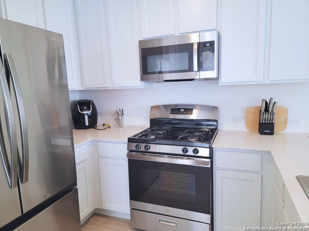 3703 Millbrook Way San Antonio, TX 78245 - Photo 3 of 10 a kitchen with stainless steel appliances granite countertop white cabinets a refrigerator a stove a microwave and wooden cabinets