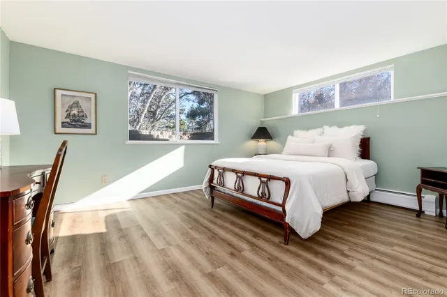 a bedroom with a bed a painting on the wall and a wooden floor