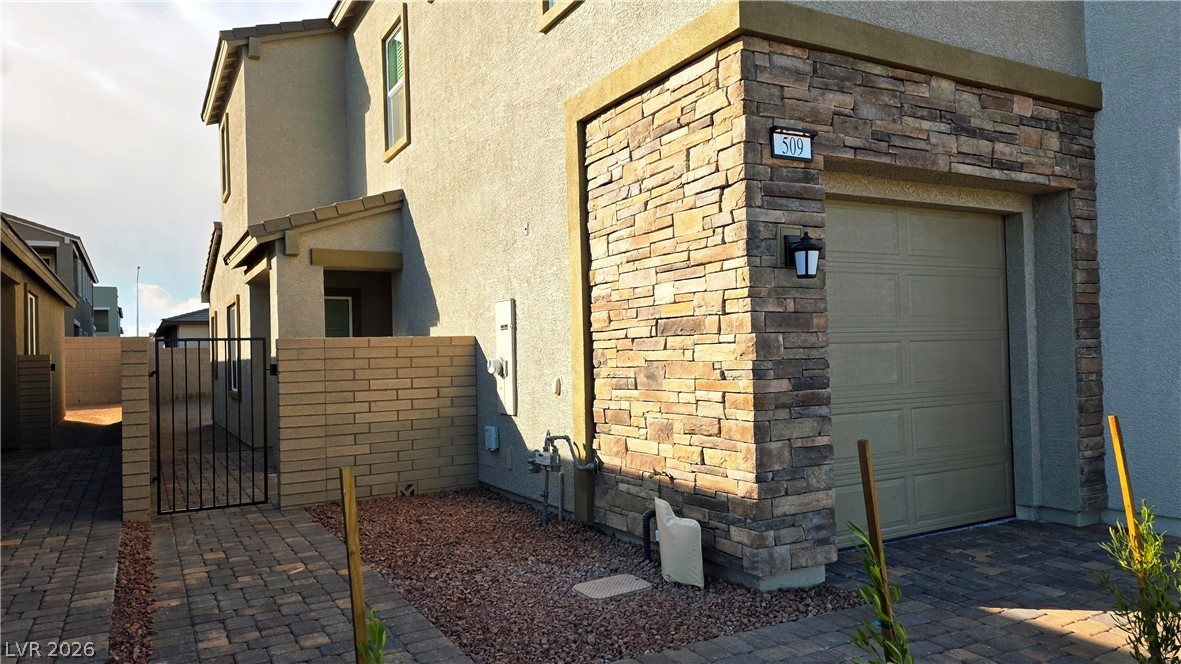 509 Arthur Pointe Street Henderson, NV 89011 - Photo 12 of 14 View of side of home featuring stone siding, stucco siding, and a gate