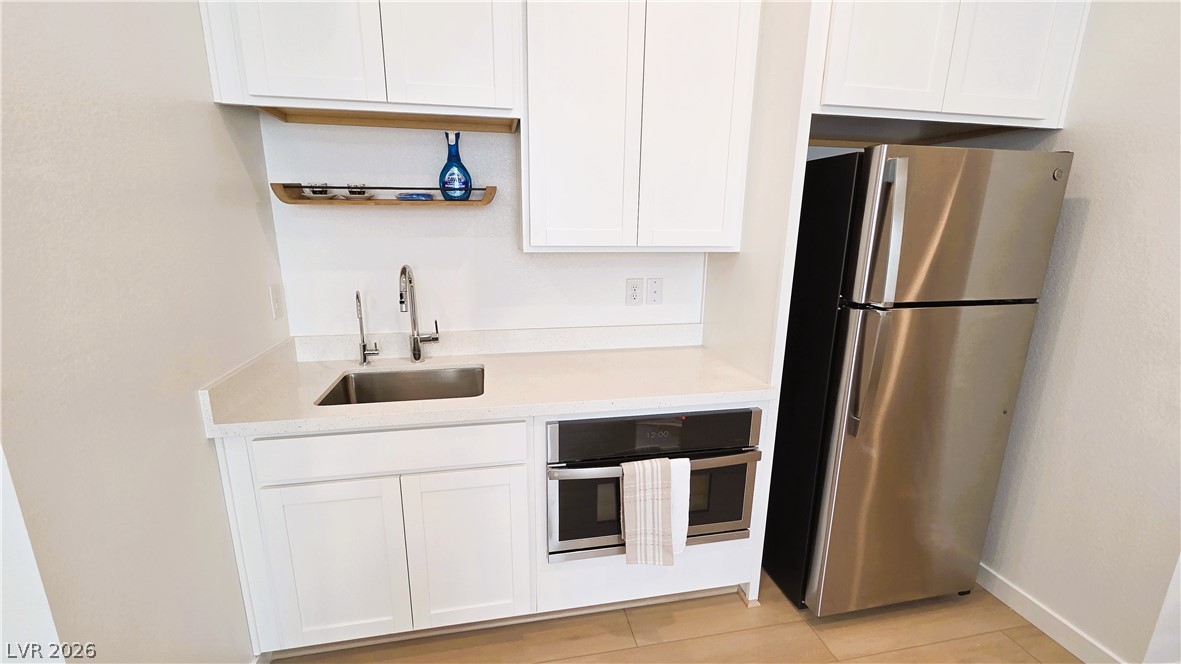 509 Arthur Pointe Street Henderson, NV 89011 - Photo 10 of 14 Kitchen featuring stainless steel appliances, white cabinets, and light stone countertops
