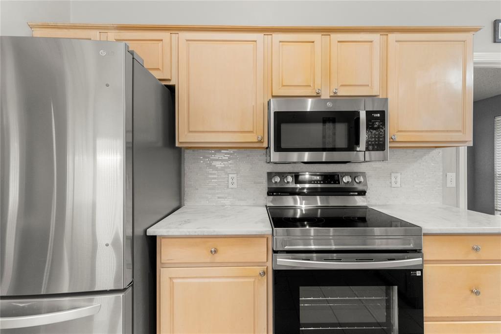 2917 Harlow Road Commerce, TX 75428 - Photo 10 of 40 a kitchen with stainless steel appliances a stove microwave and refrigerator