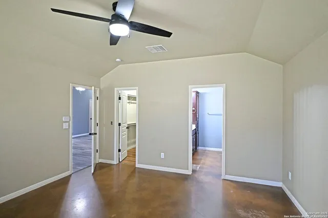 an empty room with wooden floor cabinet and a ceiling fan