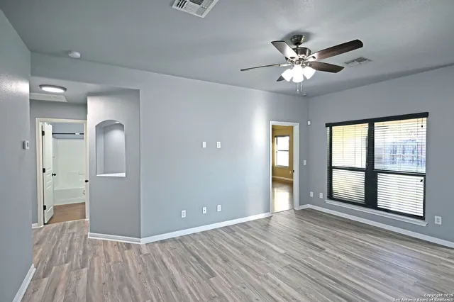 a view of an empty room with wooden floor and a window