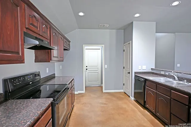 a kitchen with stainless steel appliances granite countertop a stove a sink and a refrigerator