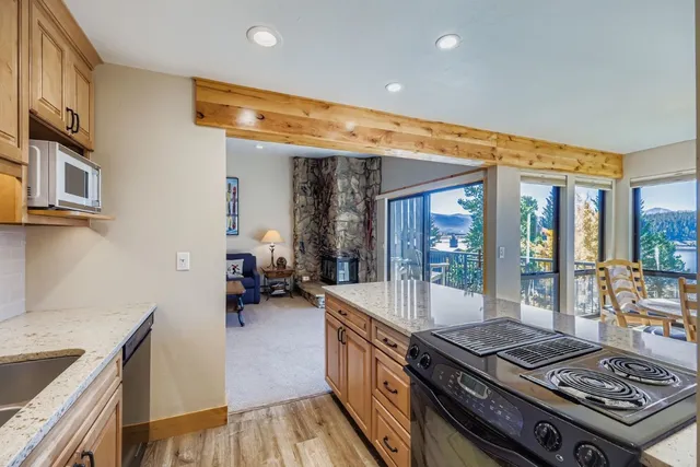 a kitchen with stainless steel appliances granite countertop a stove and a view of living room