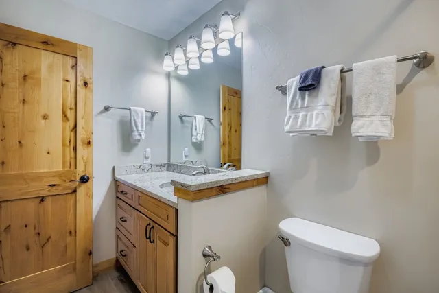 a bathroom with a granite countertop sink toilet and mirror