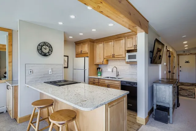 a kitchen with granite countertop kitchen island stainless steel appliances a stove refrigerator sink and cabinets
