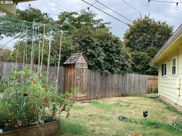 a backyard of a house with table and chairs and wooden fence