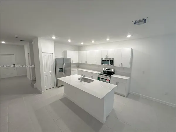 a kitchen with white cabinets and stainless steel appliances
