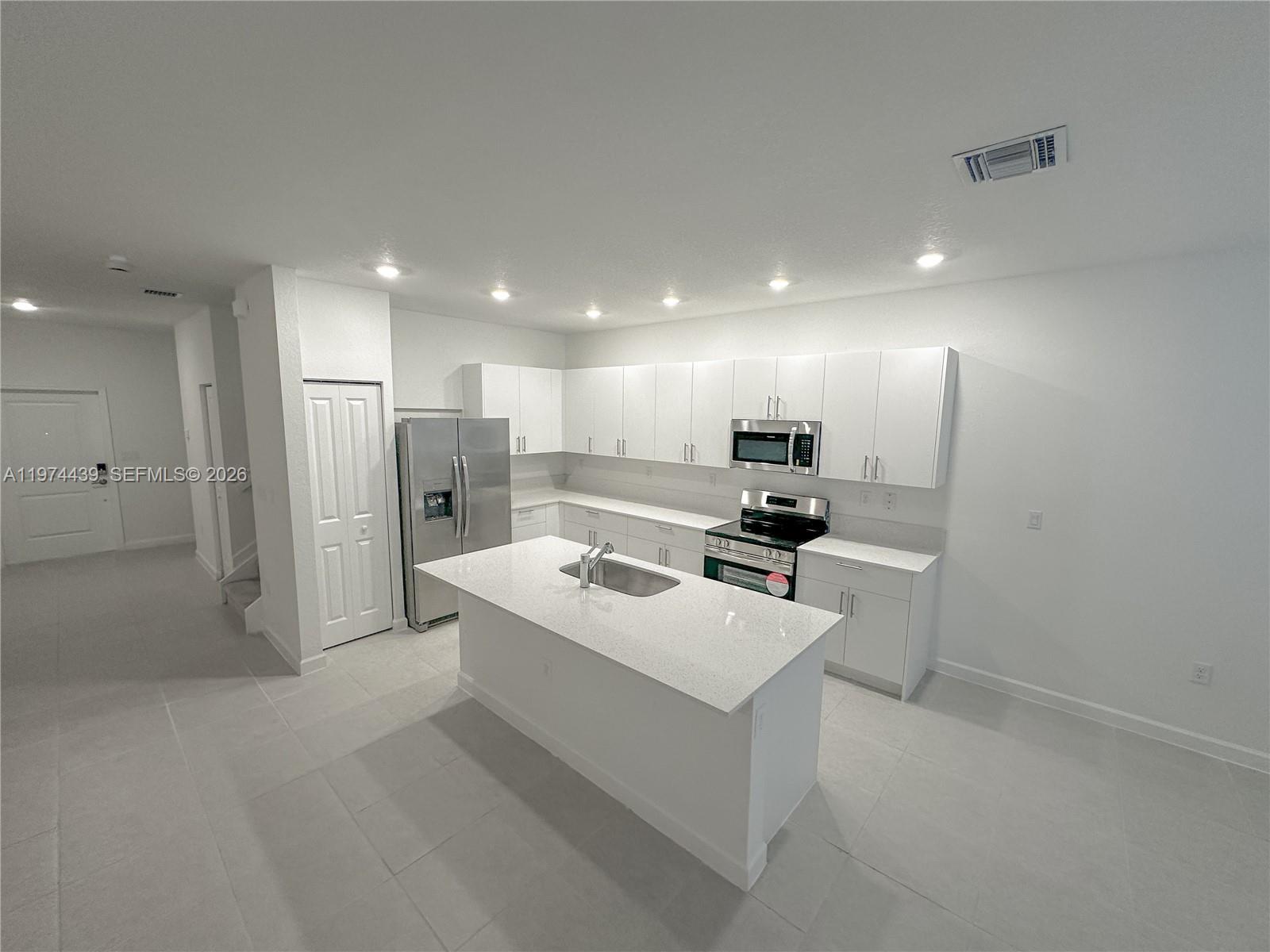 14804 Southwest 162nd Street Miami, FL 33177 - Photo 4 of 22 a kitchen with white cabinets and stainless steel appliances