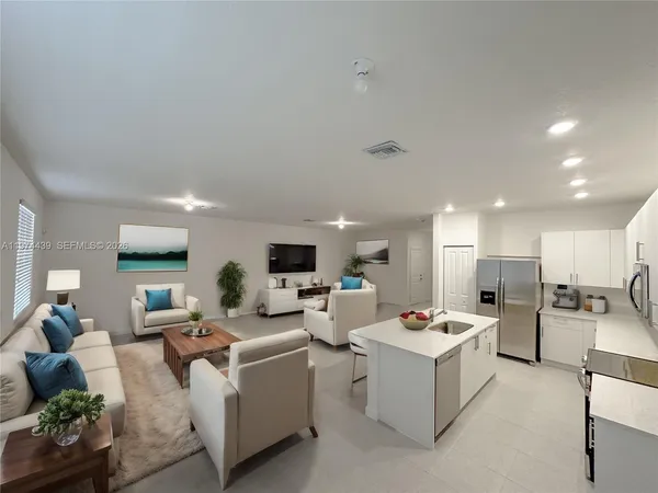 a living room with fireplace furniture and a view of kitchen