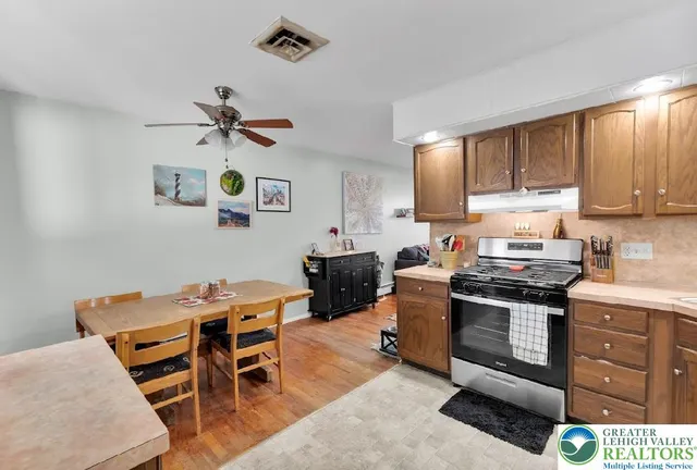 a kitchen with stainless steel appliances kitchen island granite countertop a stove top oven a sink a dining table and chairs