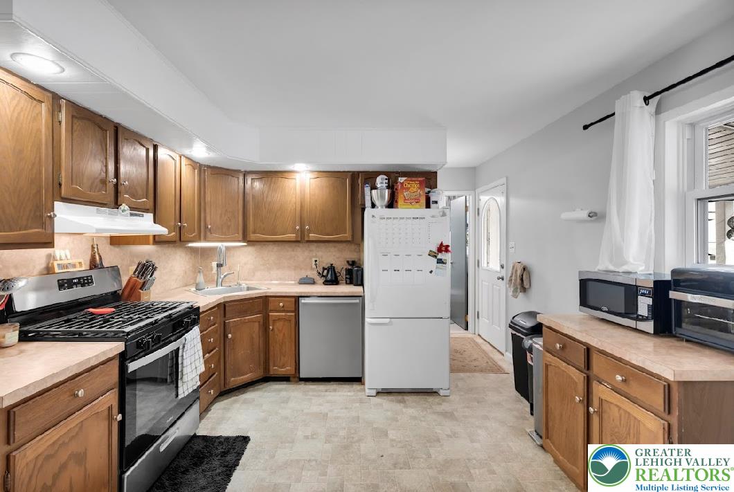 856 Poplar Road Hellertown, PA 18055 - Photo 7 of 19 a kitchen with a refrigerator a stove a sink cabinets and a window