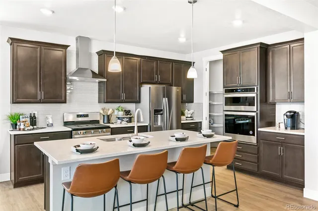 a kitchen with stainless steel appliances a dining table chairs refrigerator and cabinets