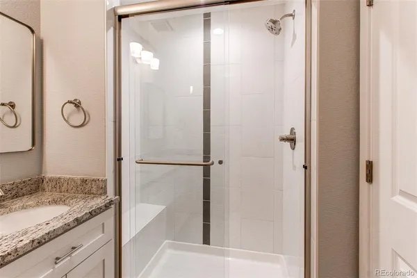 a bathroom with a granite countertop shower and a sink