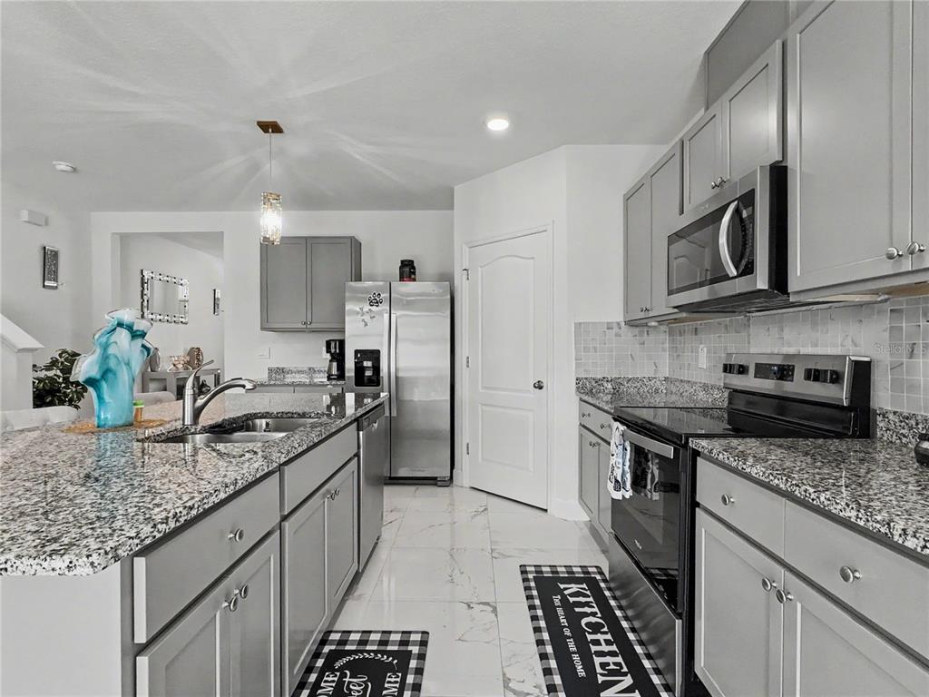 2085 Doe Run Drive Davenport, FL 33837 - Photo 14 of 44 a kitchen with stainless steel appliances granite countertop a sink stove and refrigerator