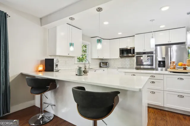 a kitchen with stainless steel appliances a sink a stove a refrigerator cabinets and a dining table