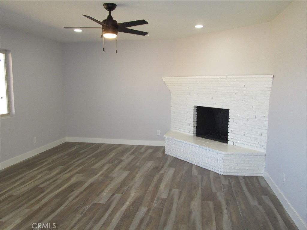 13464 Mohawk Road Apple Valley, CA 92308 - Photo 16 of 35 an empty room with wooden floor fireplace and windows